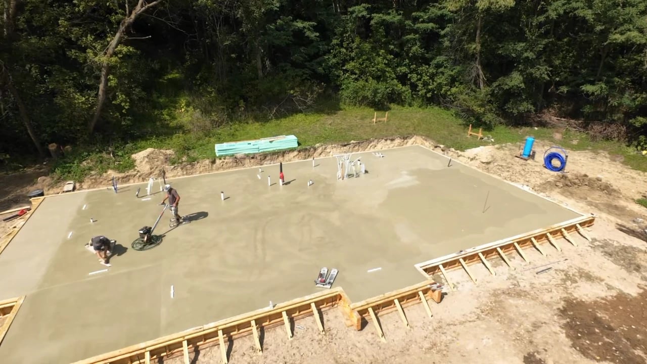 Overhead view of the concrete slab and crew at the wooded construction site