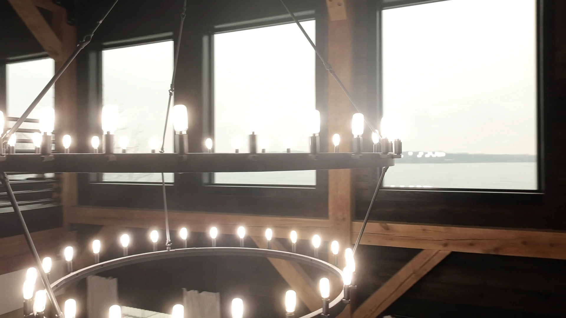 Illuminated circular chandeliers suspended beneath the timber ceiling
